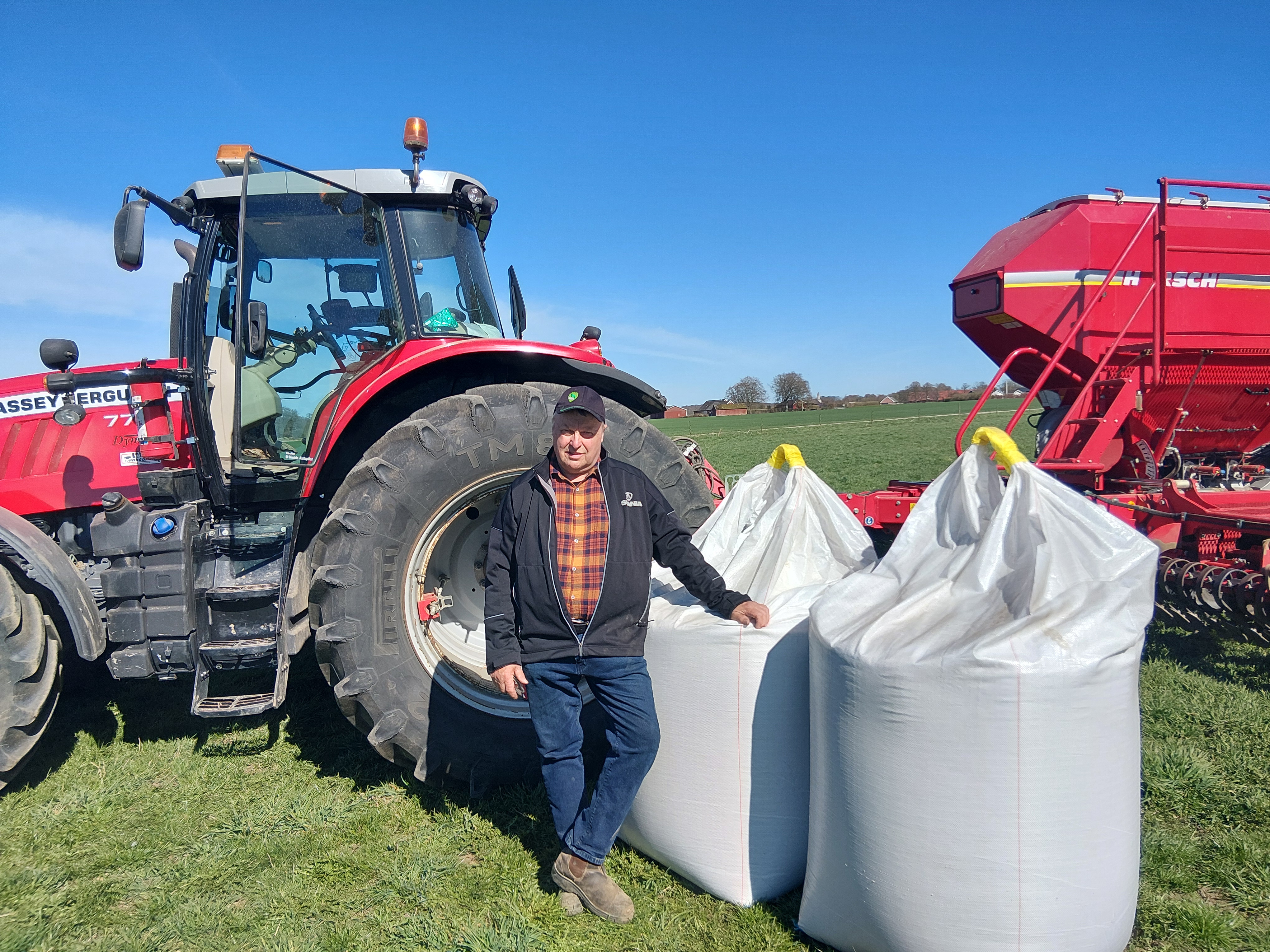 Håkan Lindquist bredvid säckar med mineralgödsel. I bakgrunden en traktor.